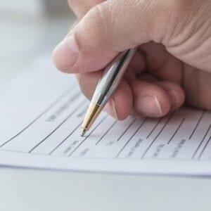 Person filling out a contractor license application form with a pen.